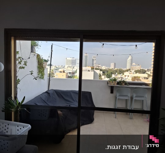 דלת הזזה מזכוכית היציאה למרפסת שמש משקיפה לנוף עירוני